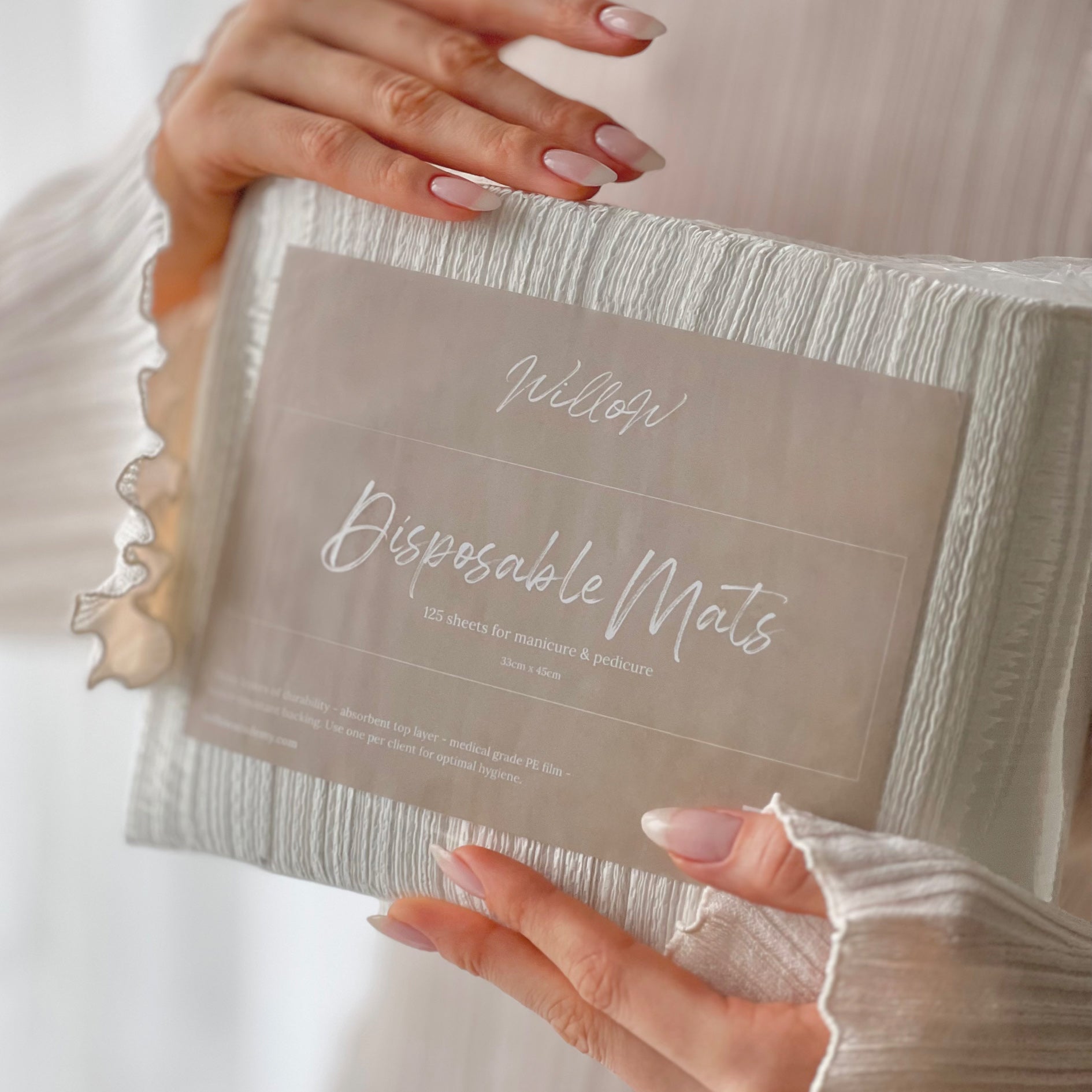 a person holding a pack of disposable mats. pack contains 125 mats for manicure and pedicure