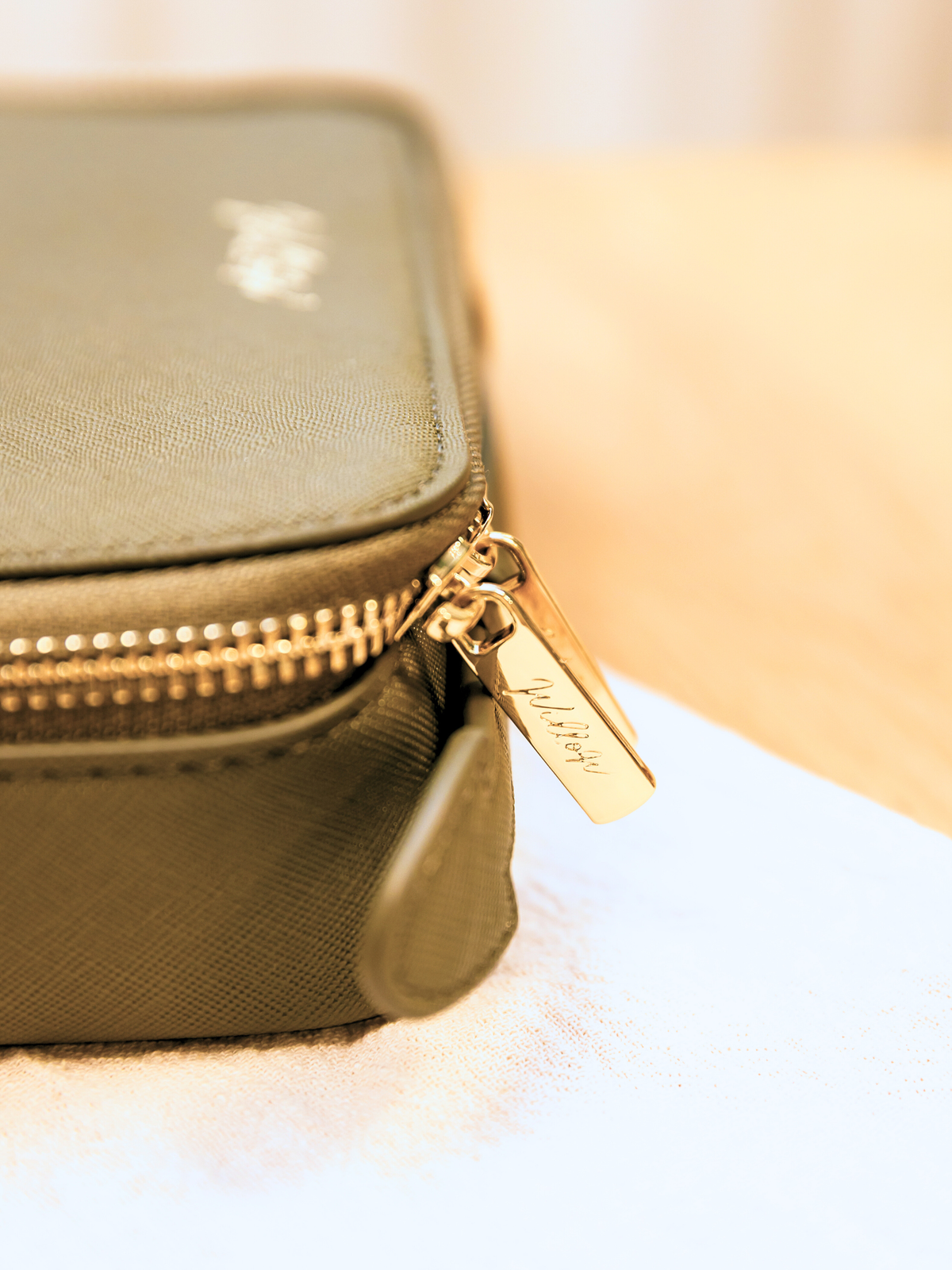 khaki travel case with gold embossed zip detail