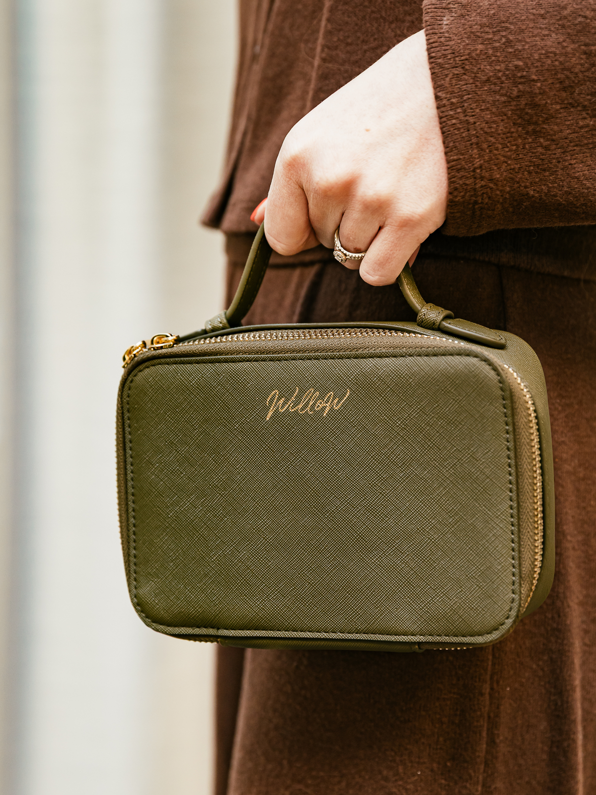 Person holding khaki travel case with gold willow branding